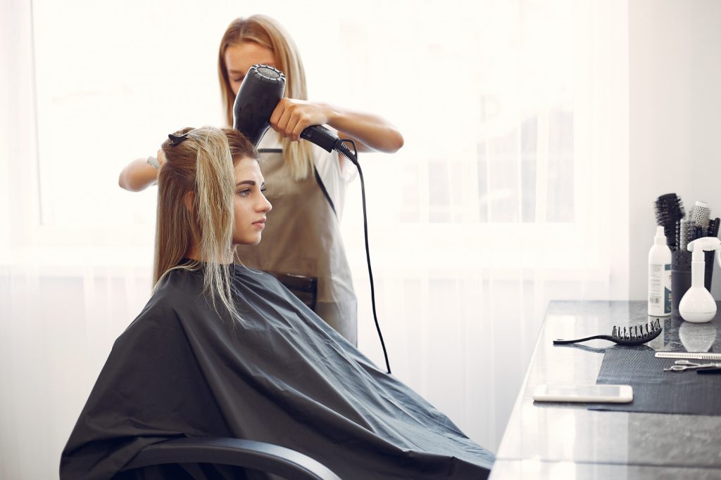 Parrucchiera che asciuga i capelli ad una cliente